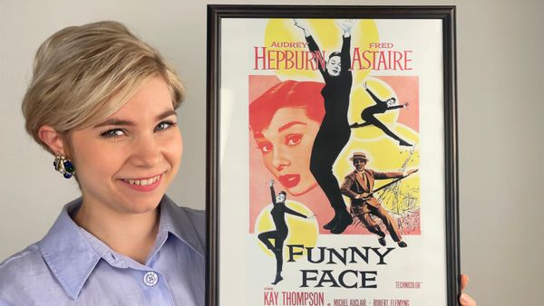 I am holding a poster of the film "Funny Face" and smiling
